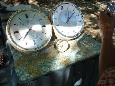 Photo showing three clocks of different sizes, each ringed in metal, placed on a multicolored fabric base.